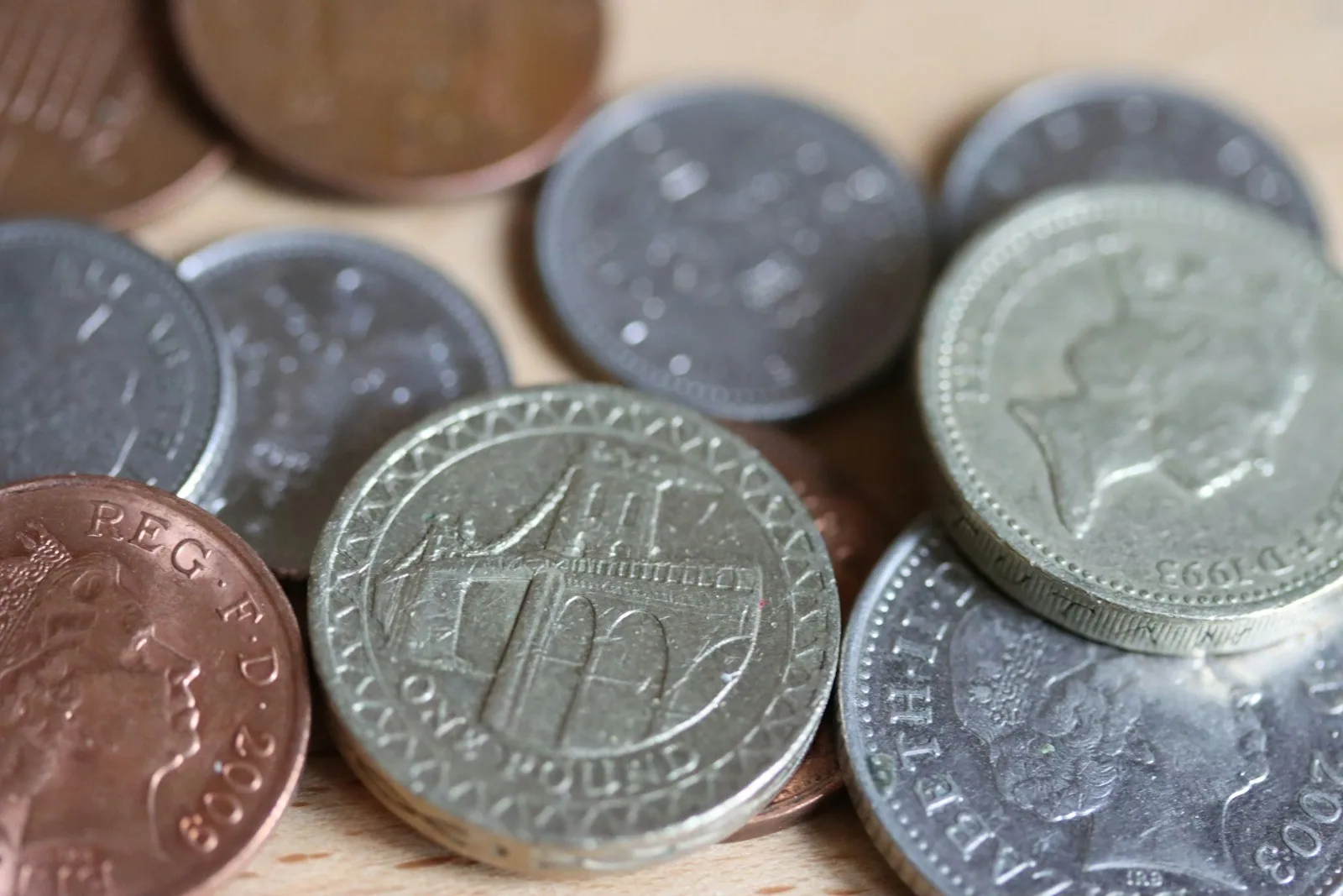British coins on a wooden table Pile of British coins on a wooden table