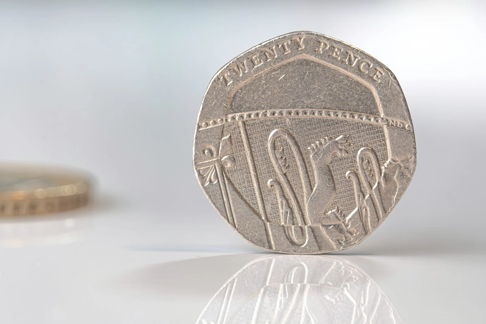 Upright 20p coin UK twenty pence coin standing upright on a reflective surface
