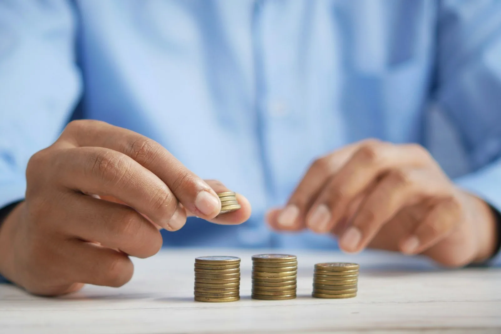 Stacking coins on a table Person stacking coins on a table