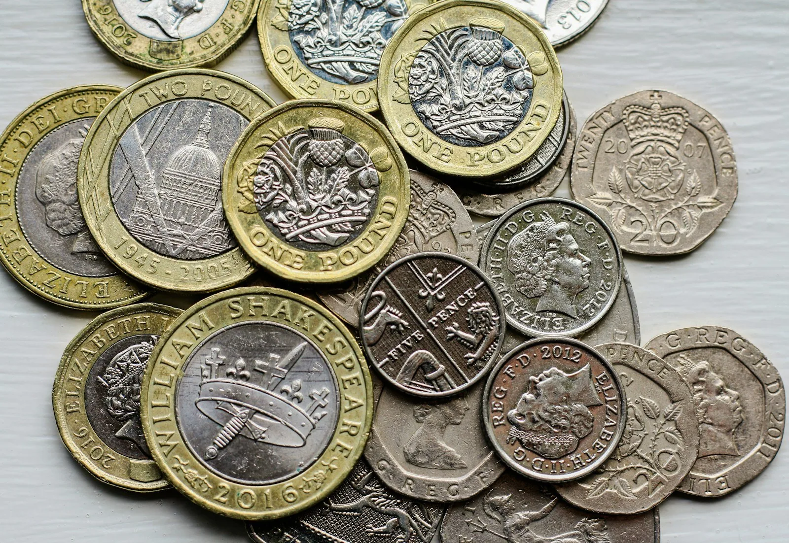 Pile of UK sterling coins including one pound, five pence and twenty pence pieces