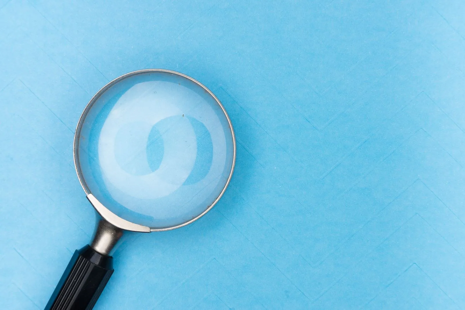 Magnifying glass on blue Close-up of a magnifying glass on a blue surface