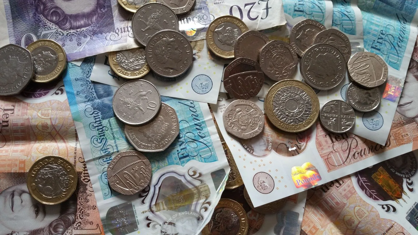 Round coins lying on British banknotes