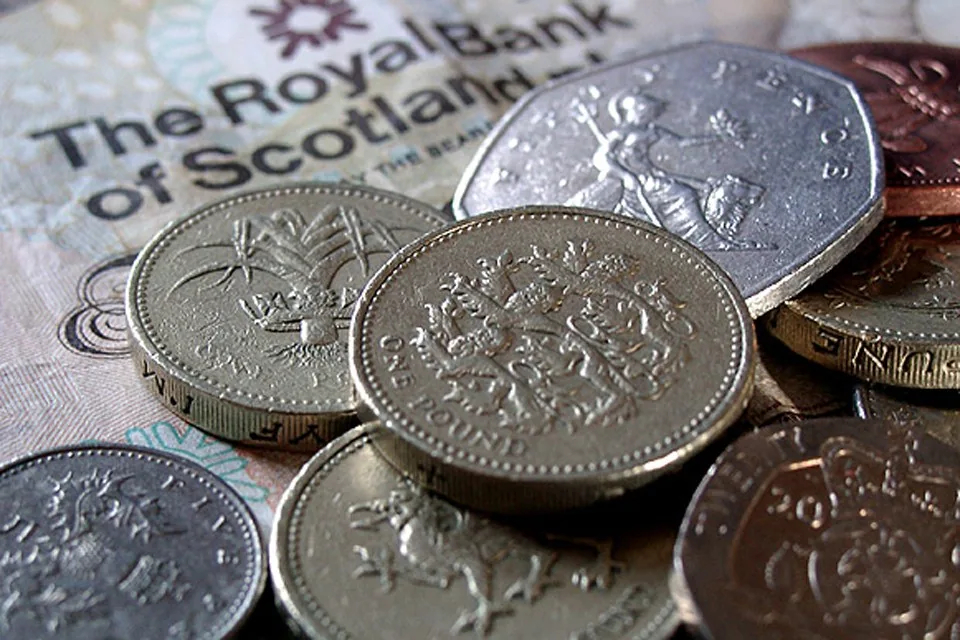 A small group of UK coins lying on a banknote A small group of UK coins lying on a banknote